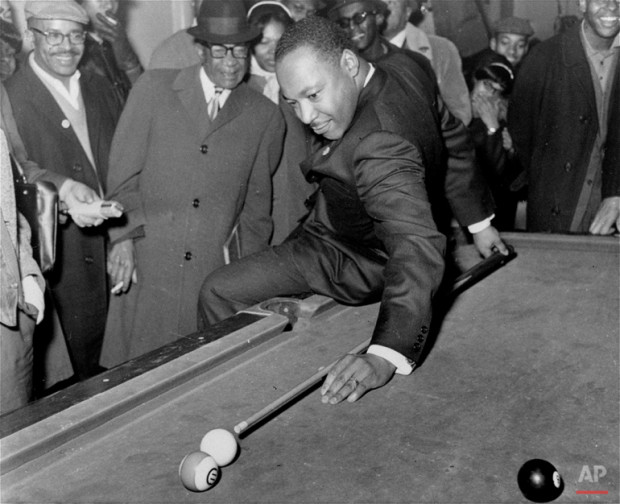 During a visit to a pool hall, February 18, 1966, Dr. Martin Luther King, Jr., campaigning in Chicago, IL. for better living conditions for African Americans, demonstrates some proficiency with a cue. (AP Photo)
