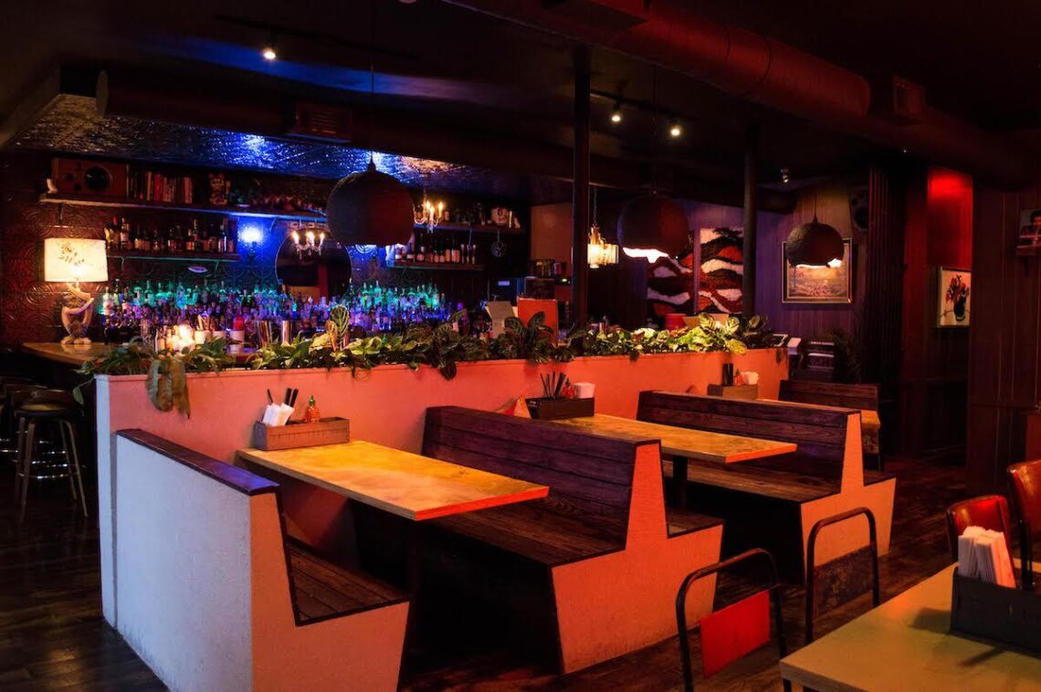 Interior of Bon Ton restaurant in Midtown Atlanta with pink walls, patterned tablecloths and hanging lights