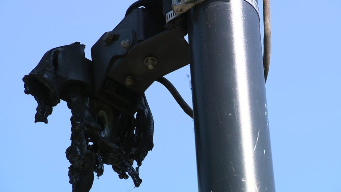 Close-up of a fire-damaged Flock Safety camera mounted on a pole in Cobb County.