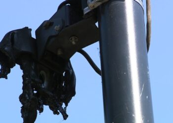Close-up of a fire-damaged Flock Safety camera mounted on a pole in Cobb County.