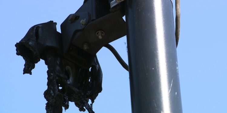 Close-up of a fire-damaged Flock Safety camera mounted on a pole in Cobb County.