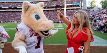 A woman holding a GAFollowers microphone poses with the Oklahoma Sooners mascot on the field at Sanford Stadium before Georgia's 41-13 win over Oklahoma.