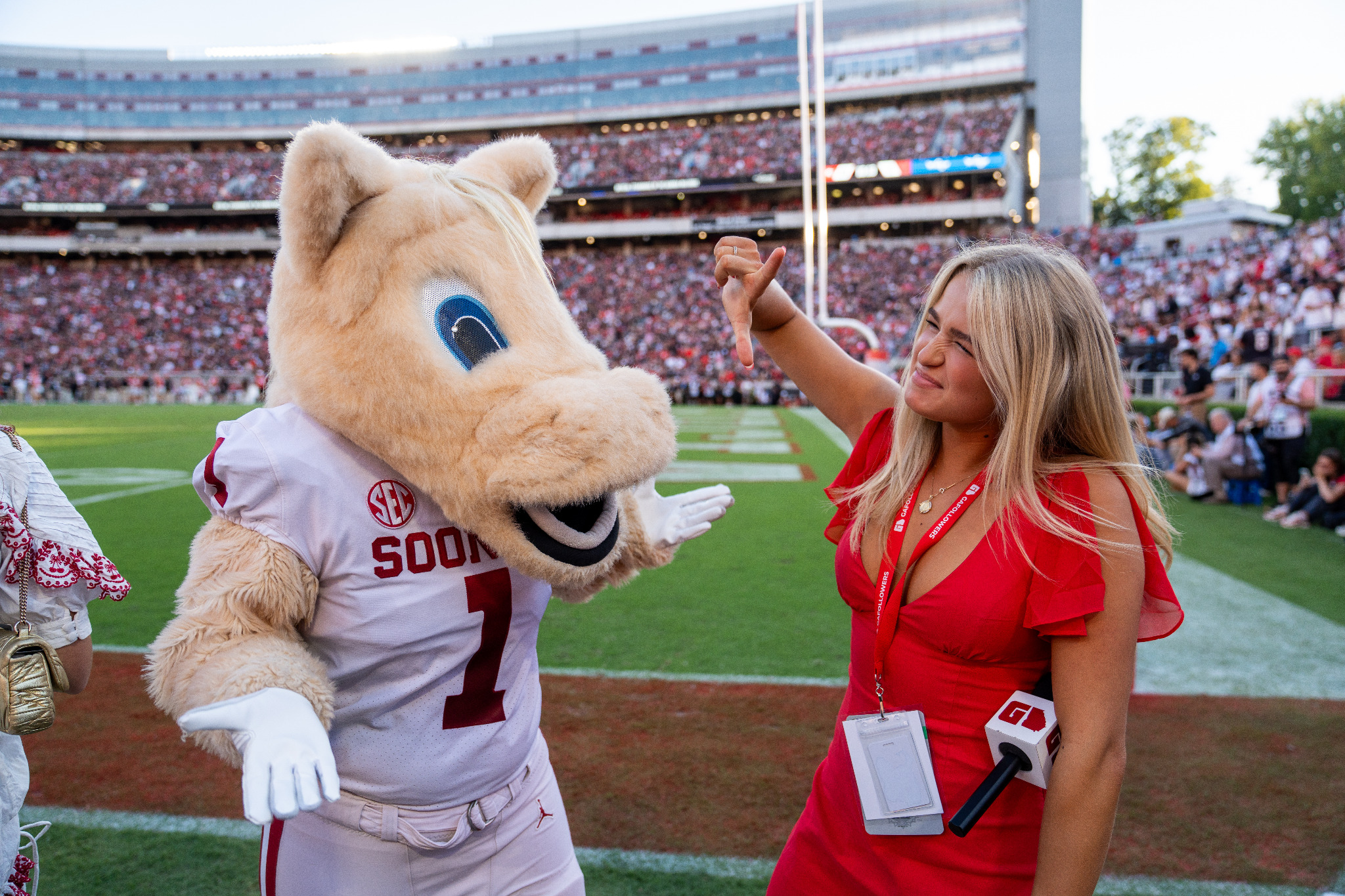A woman holding a GAFollowers microphone poses with the Oklahoma Sooners mascot on the field at Sanford Stadium before Georgia's 41-13 win over Oklahoma.