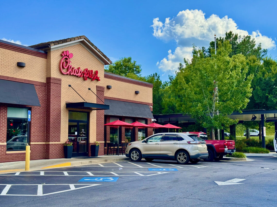 Exterior of a Chick-fil-A restaurant in Cornelia, Georgia, with parked cars and a drive-through canopy.